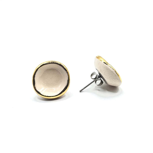 Two Camelia white ceramic stud earrings with gold rims on a white background