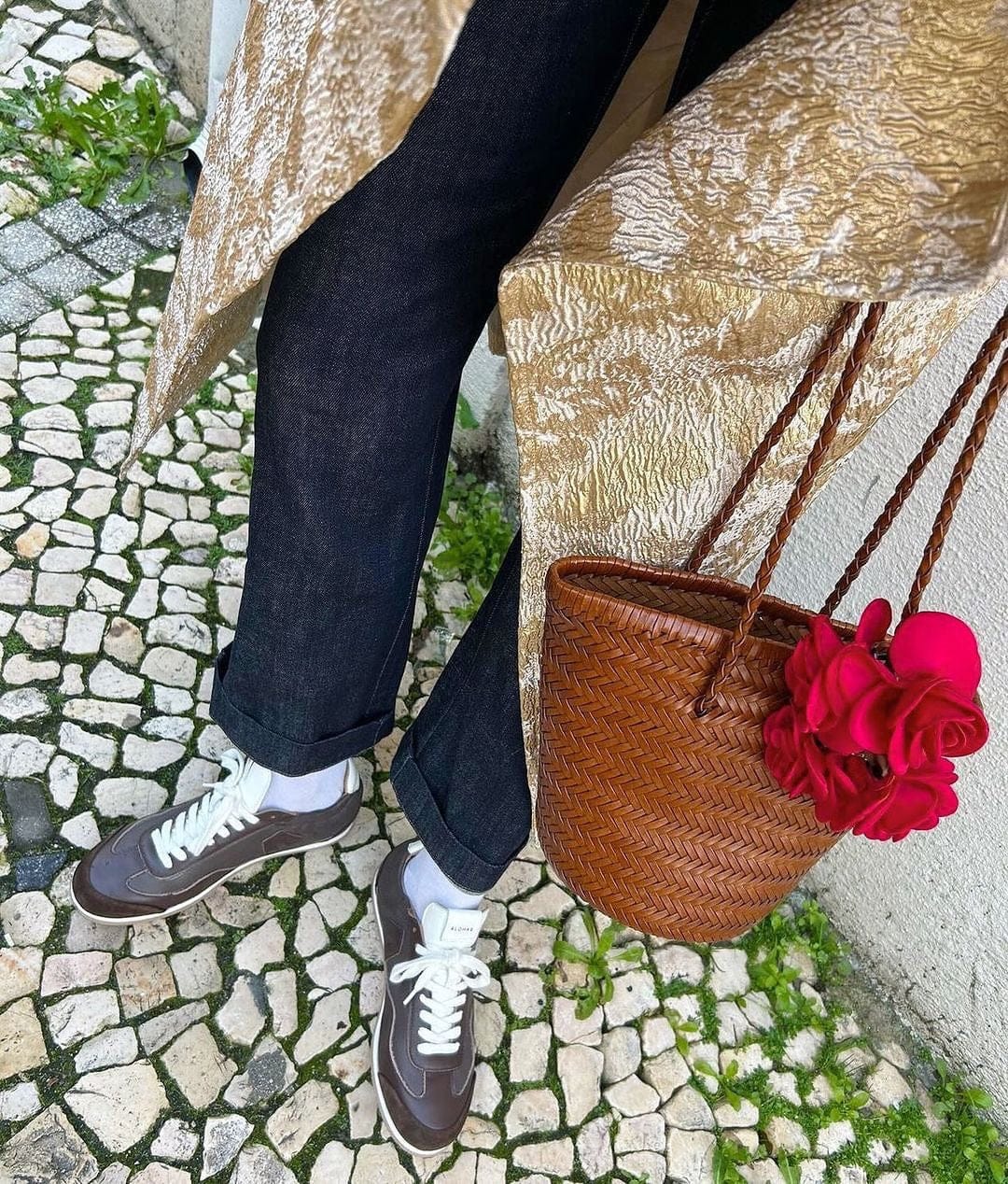 Bruin handwoven leather shoulder bucket bag with braided straps and a bright pink flower accessory