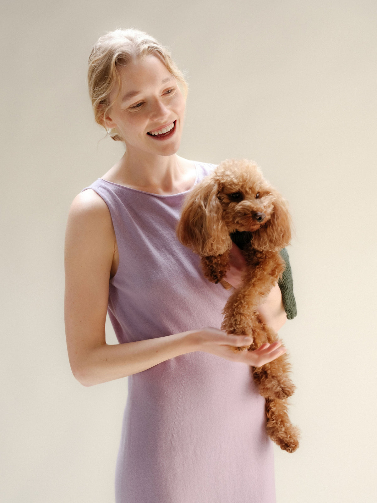 Modelo con lavanda cashmere blend boat neck sleeveless dress holding a small brown poodle
