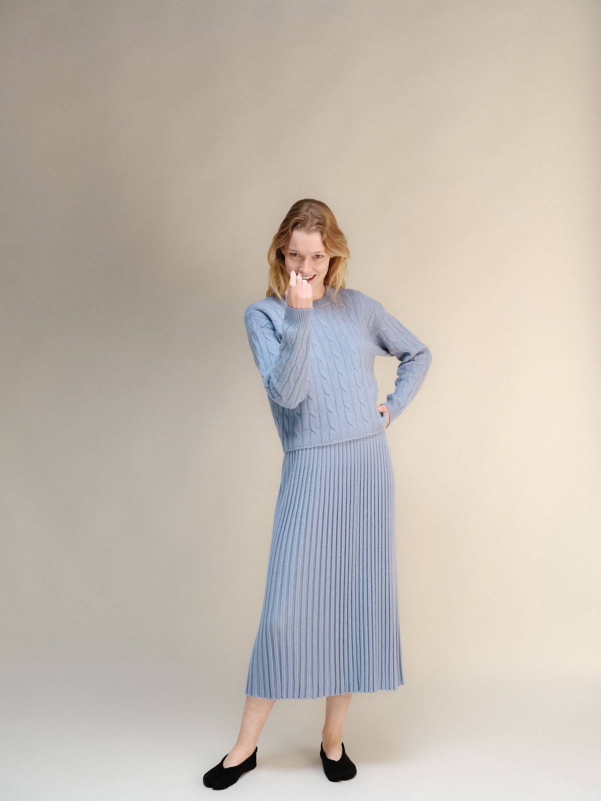 Modelo con azul pálido cashmere blend jersey de punto trenzado with a falda midi acanalada a juego.