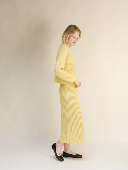 Vista lateral of a mujer con a amarillo pálido cashmere blend knit skirt with a jersey a juego against a neutral backdrop.