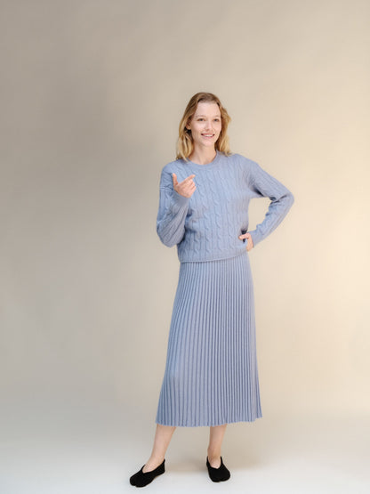 Modelo con a azul empolvado knit sweater with a falda midi acanalada a juego in a neutral studio.