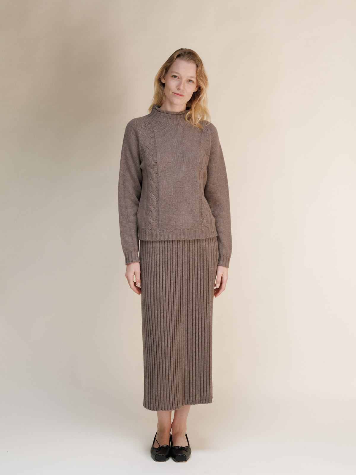 Modelo con a taupe cashmere blend knit sweater and matching falda larga acanalada against a neutral backdrop.