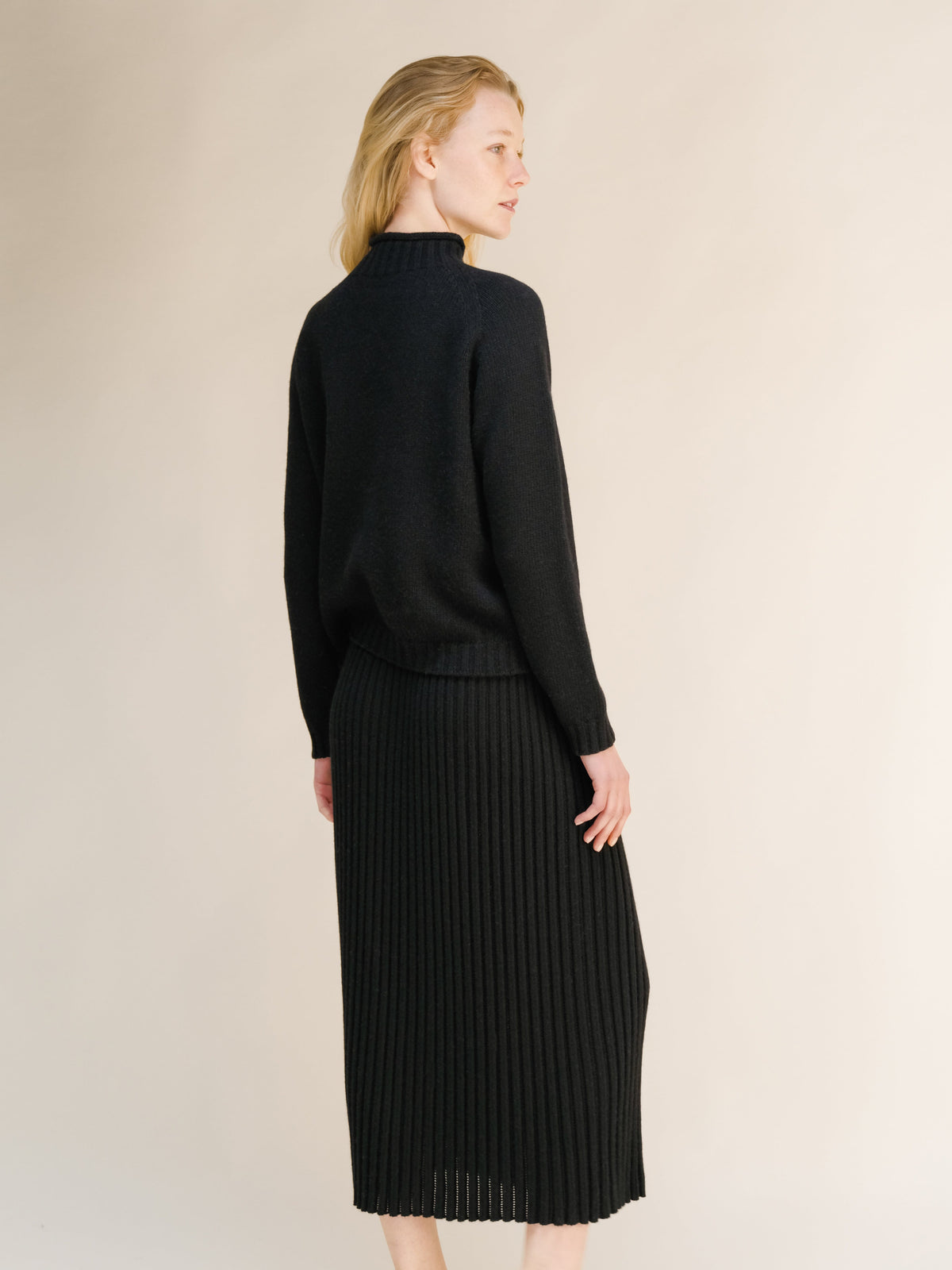 Back view of a modelo con a black cashmere blend perforated 3D-knit skirt.
