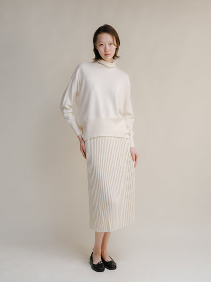 Crema jersey de cuello alto knit sweater with a falda midi acanalada a juego.