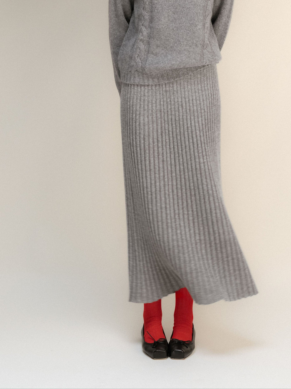 Gray falda maxi de mezcla de cachemira en punto 3D with a bajo acanalado, combinada con red socks and black flats.