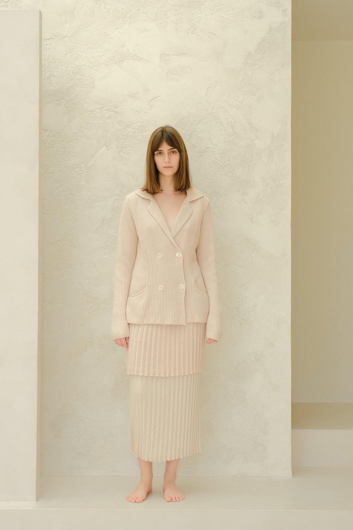 Modelo con a beige falda larga plisada de algodón fino with a matching double-breasted blazer de punto