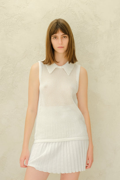 Modelo con a white mesh sleeveless top with a collared neckline and a white plissé minifalda.