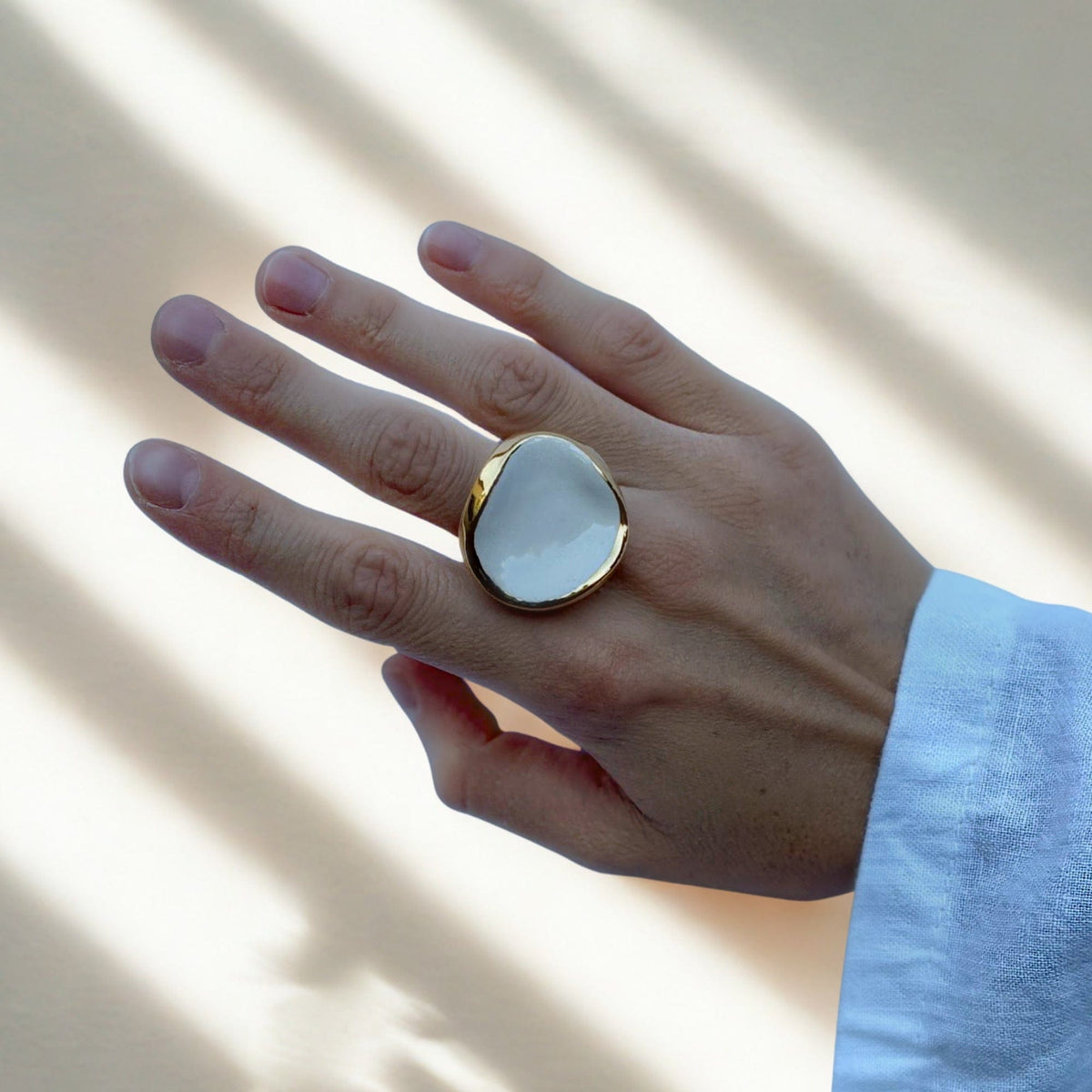Leda Ring am Finger mit weißem Keramikelement in goldfarbener Einfassung