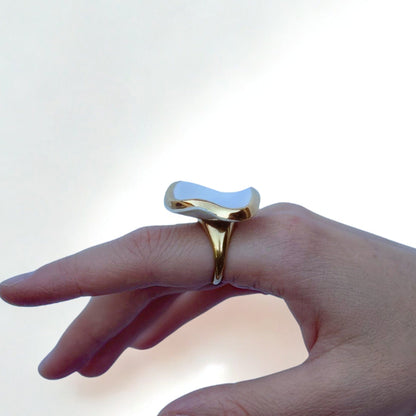Goldfarbener Ring mit glänzendem unregelmäßigem weißem Keramikelement am Finger