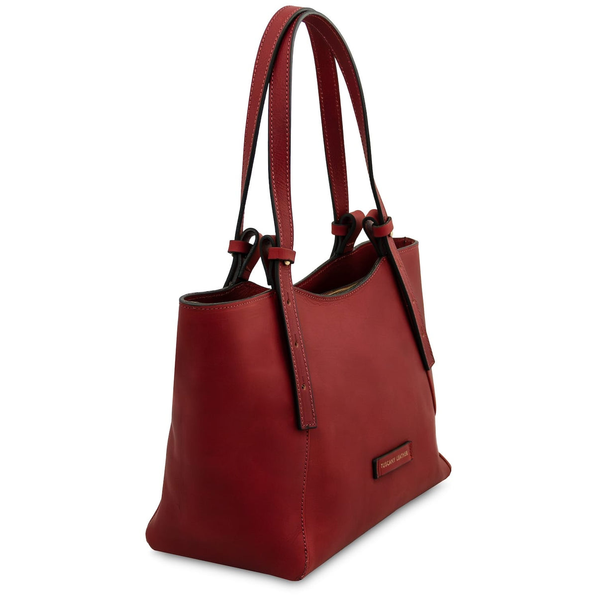 Angled side view of the red Libra leather tote with double handles and stitched panels.