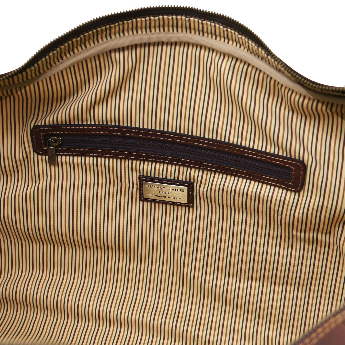 Interior close up showing a bolsillo con cremallera with dark leather trim on striped lining.