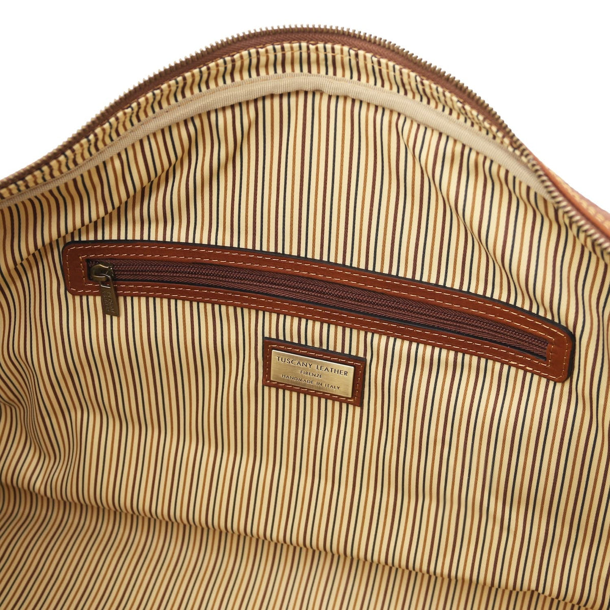 Interior close up with striped lining brown leather bolsillo con cremallera and metal tag.