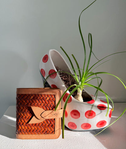 Lumi - Handwoven Leather Wallet | Taupe & Kaffee featuring woven leather texture with smooth taupe leather trim beside a white planter with red dots and green plant
