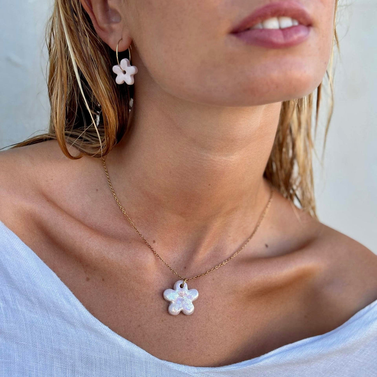 Model wearing Mimì pink floral ceramic dangle earrings with matching flower pendant necklace