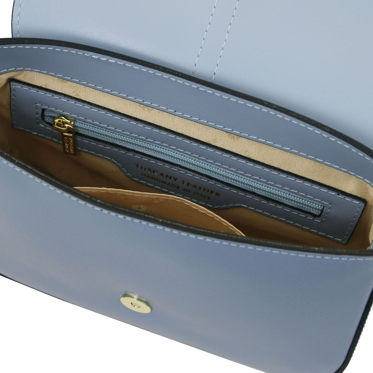 Inside view of Nausica bag showing beige lining and a blue zip pocket with gold pull