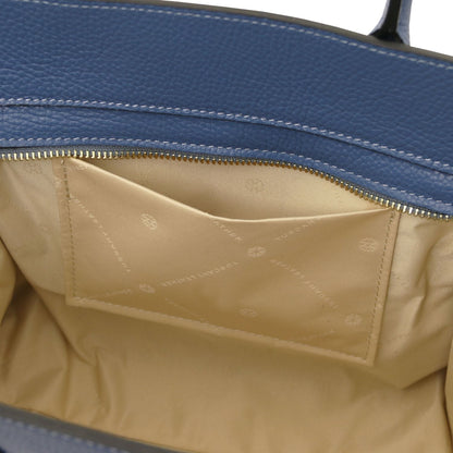 Open view of blue leather tote showing beige fabric interior pocket with subtle branding and detailed stitching inside zippered compartment.