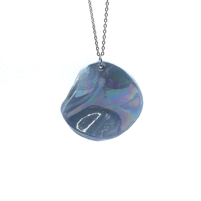 Collana con pendente in ceramica blu iridescente su catena argentata, sfondo bianco