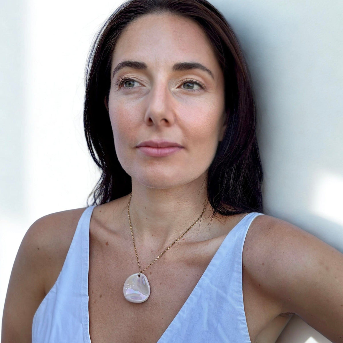 Model wearing the Perla handcrafted pearl pink ceramic necklace on a delicate gold chain