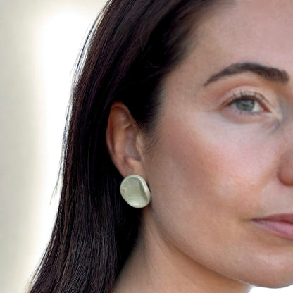 Closeup of a mujer con a sage-green ceramic stud earring