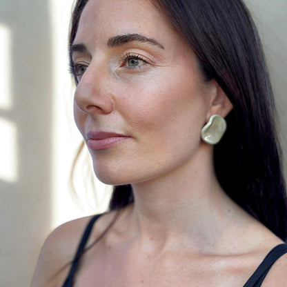 Profile view of a mujer con the sage-green ceramic stud earring