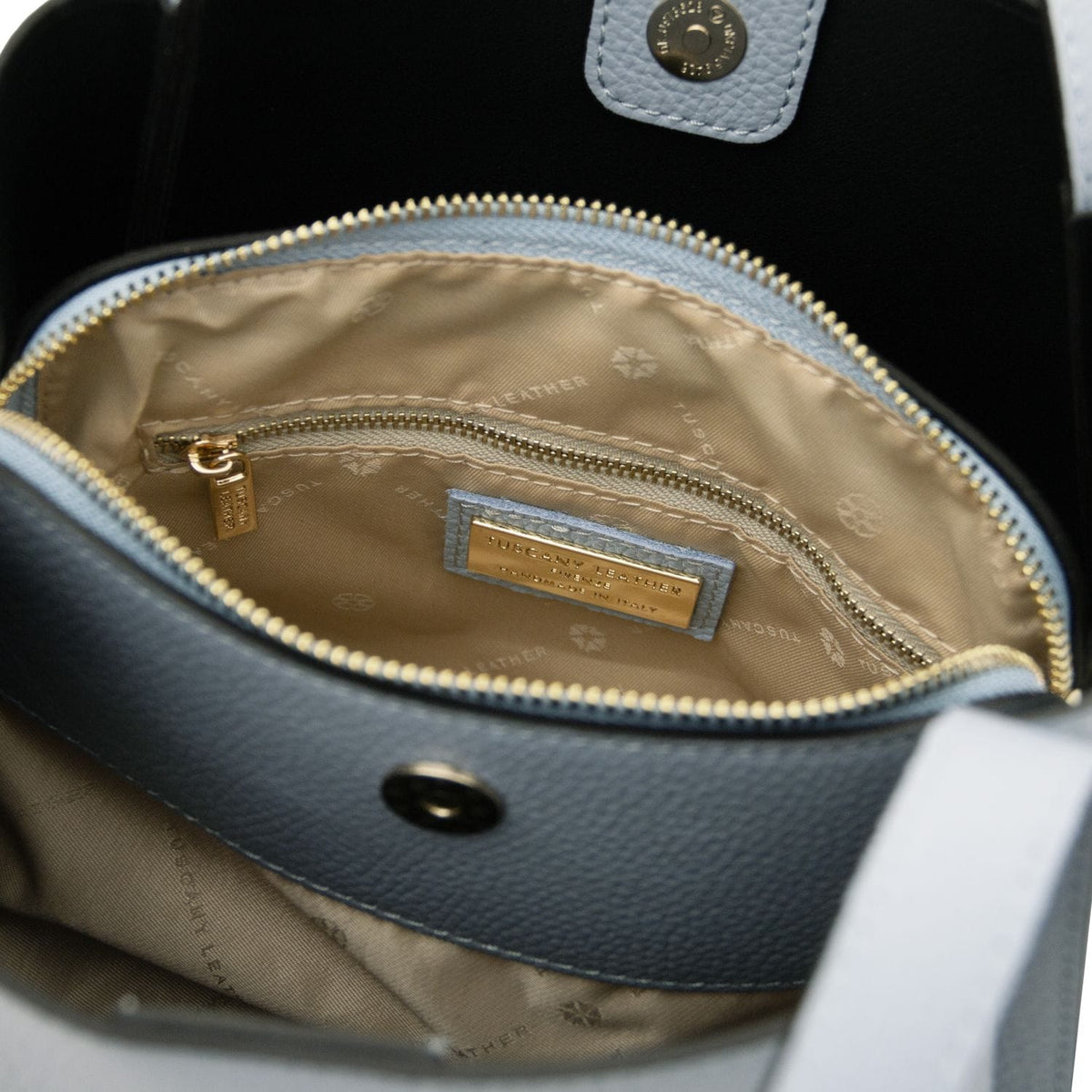 Vista interna of the Soave hebag con fodera beige, tasca con zip e a gold label plaque.