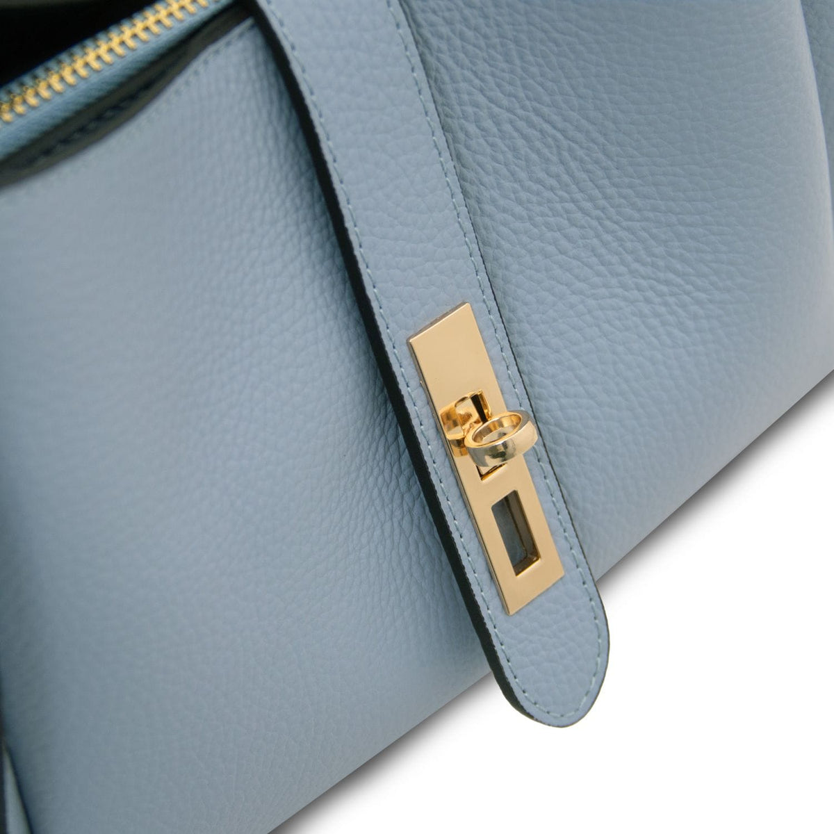 Primo piano of azzurro pallido leather con accessori metallici color oro e zipper edge on Soave hebag.