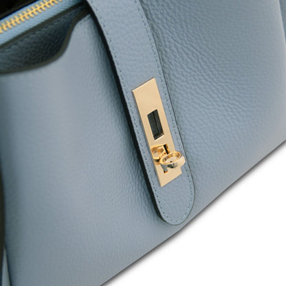 Primo piano of azzurro pallido strap con accessori metallici color oro on Soave hebag.