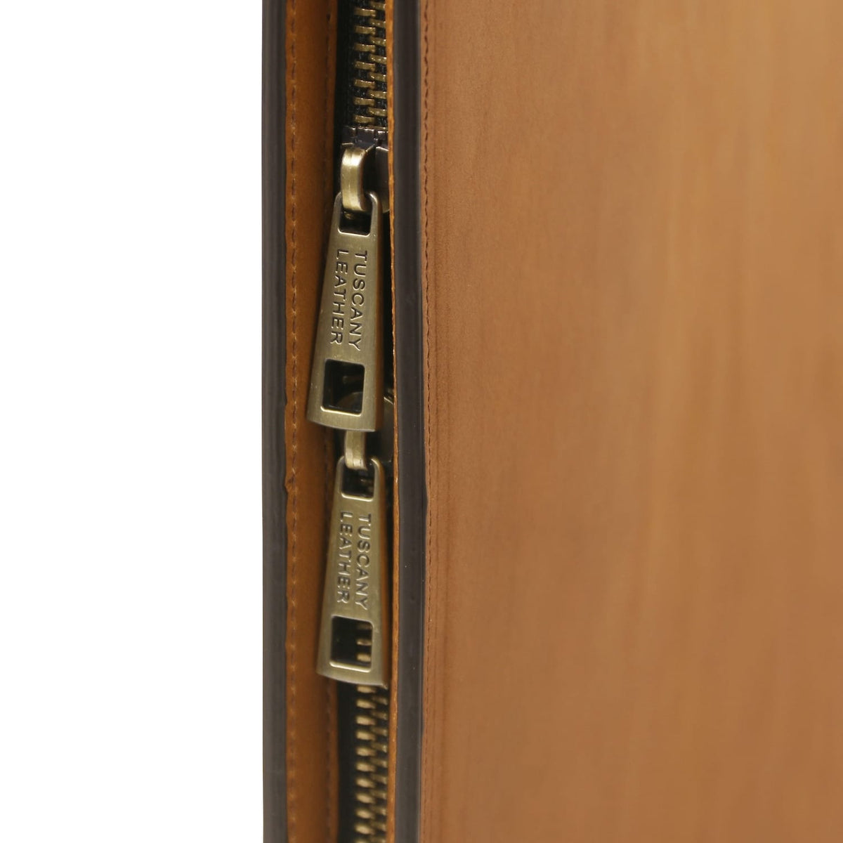Close-up of dual brass zipper pulls on tan leather document case.