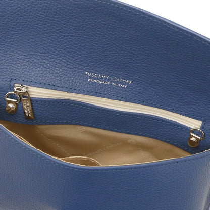 Close-up of blue leather clutch toont inner ritsvak with beige voering and goudkleurige ritstrekker.