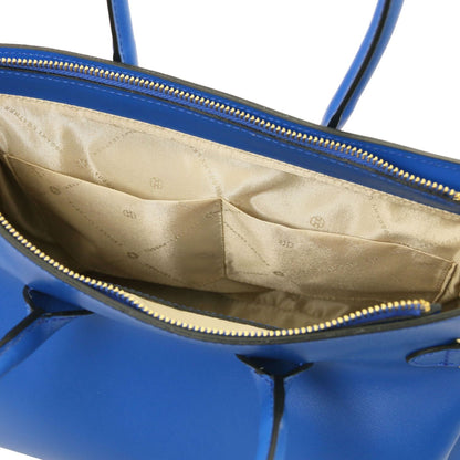 Open view of blue leather handbag showing beige fabric interior with stitched pockets and gold zipper closure