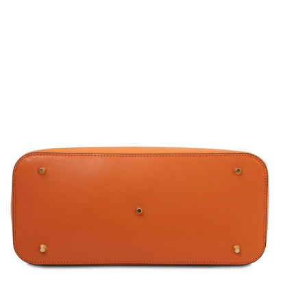 Bottom view of a structured tan leather handbag showcasing gold-tone metal feet and detailed stitching.