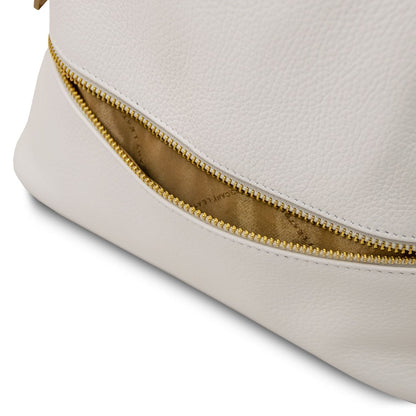 Close-up of a gold zipper along the side seam of the white leather bag