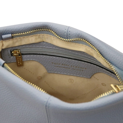 Primo piano of azzurro pelle morbida shoulder bag interior showing beige fodera in tessuto, tasca con zip, e gold-tone zipper pull.