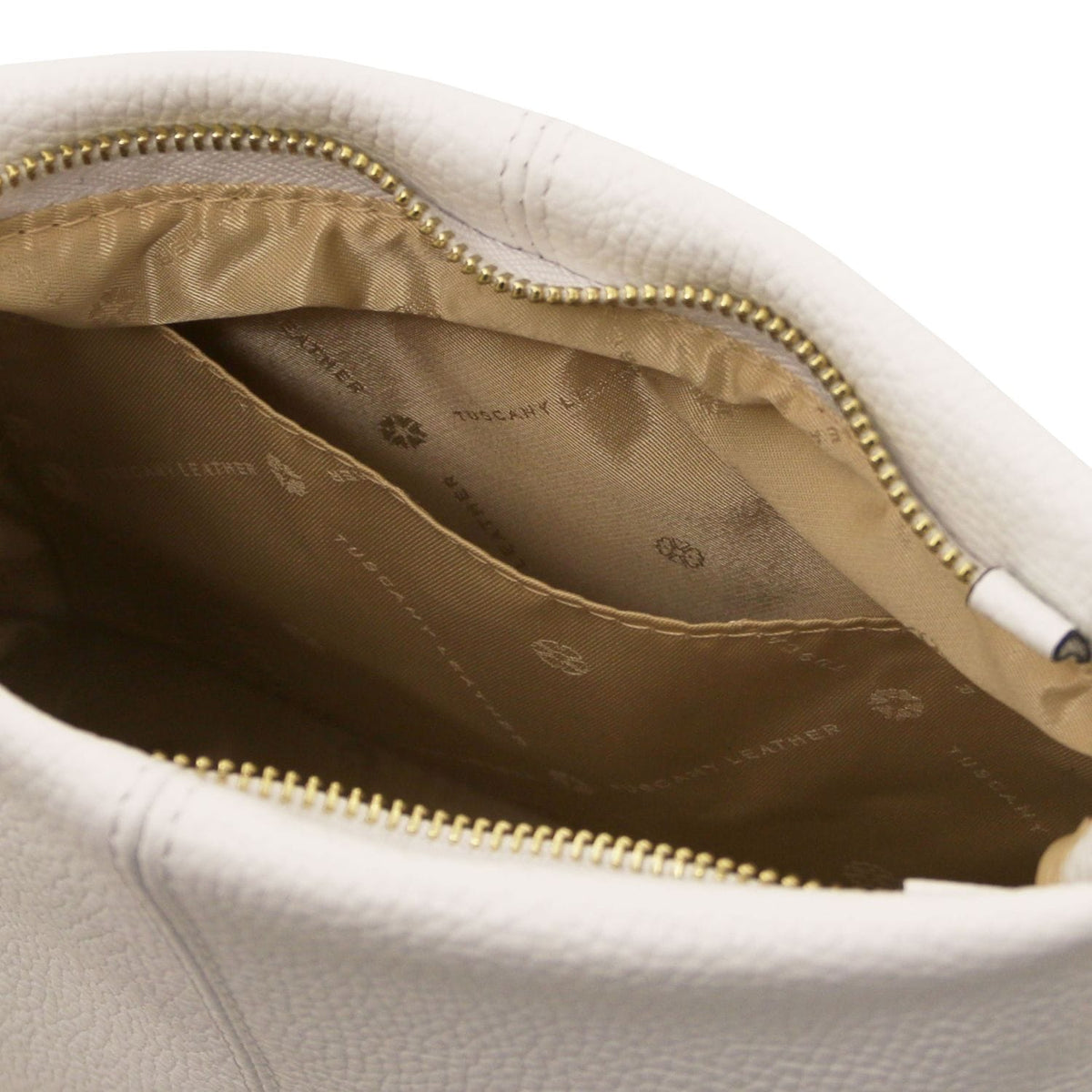 Primo piano of soft bianco leather bag interior con beige fodera in tessuto e zip color oro detailing.