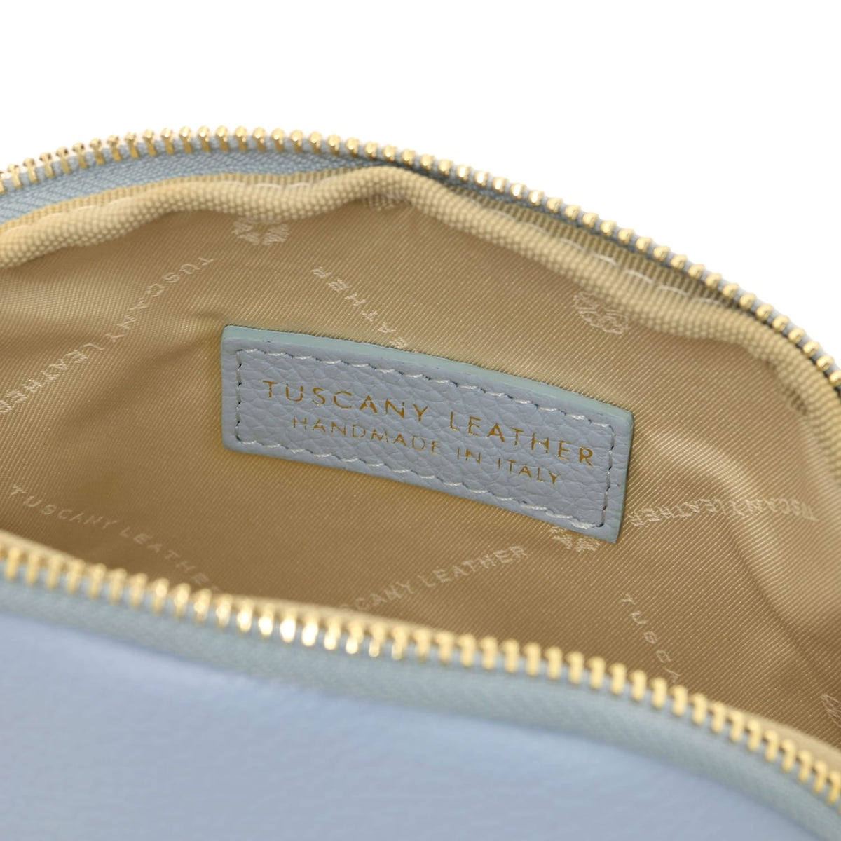 Primo piano of a pelle morbida toiletry case interior showcasing beige fodera in tessuto e stitched Tuscany Leather label inside zipper closure.