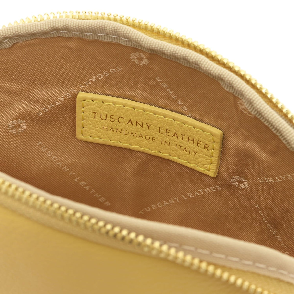 Primo piano of pelle morbida toiletry case interior showing fodera in tessuto e stitched Tuscany Leather label inside zipper opening.