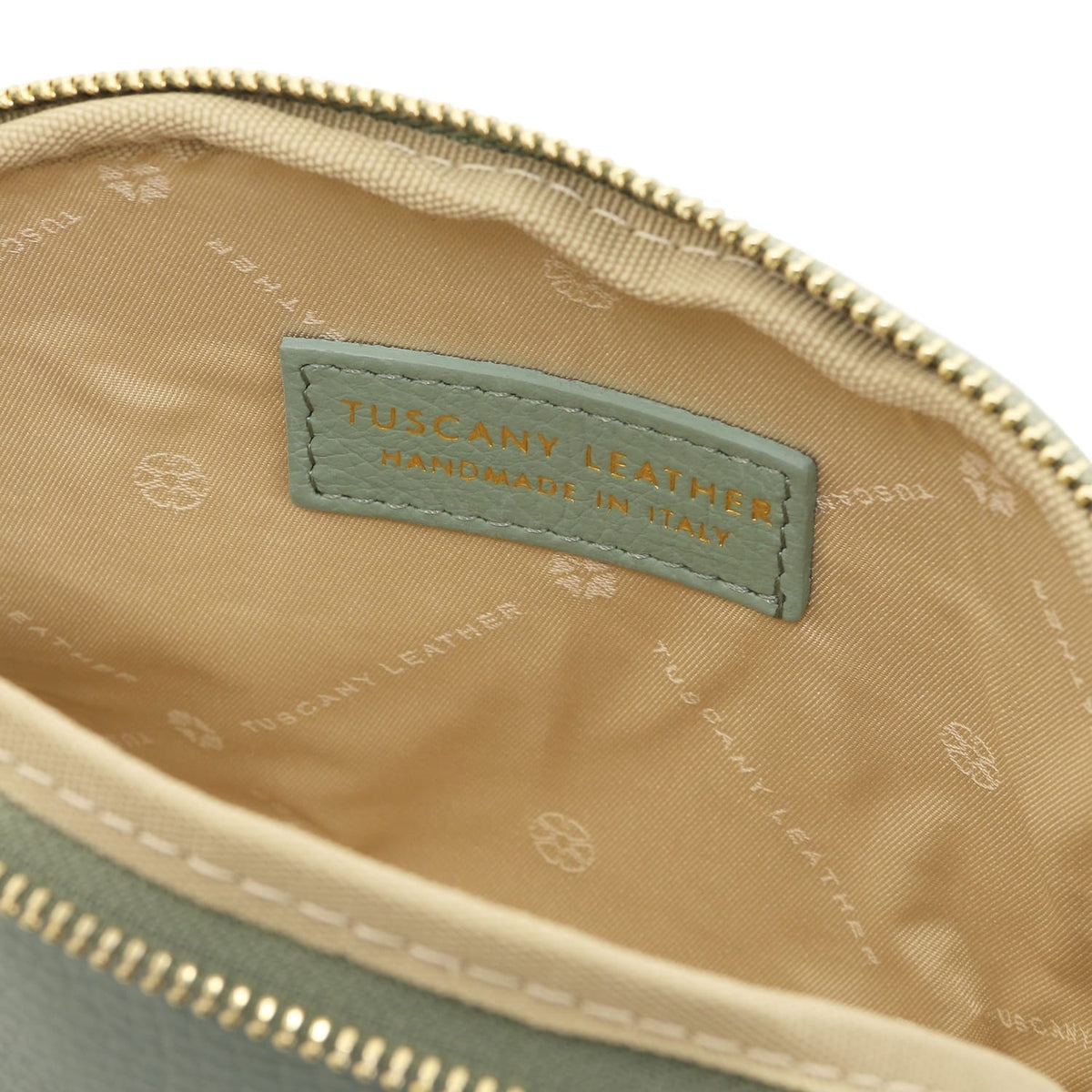 Primo piano of beige fabric interior con Tuscany Leather label stitched inside pelle morbida toiletry case.