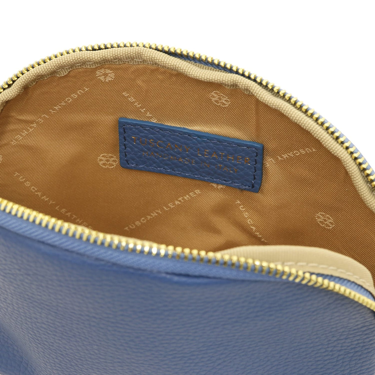 Primo piano of blu leather toiletry case interior showing beige fodera in tessuto e embossed Tuscany Leather made in Italy label.
